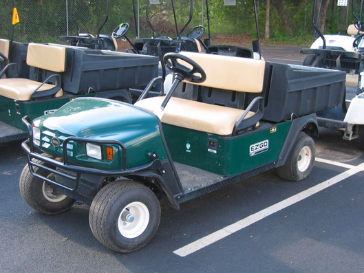 A green utility vehicle in a parking lot of UTVs.