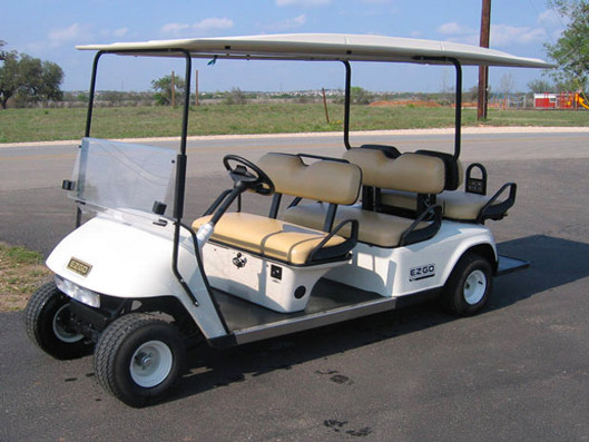 A white six seater golf cart on a lot.